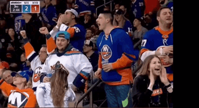 a crowd of people watching a hockey game with the score being 2 to 1