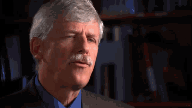 a man with gray hair and a mustache has a red circle on his neck