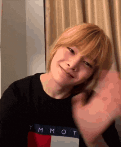 a young man with blonde hair wearing a black tommy hilfiger shirt
