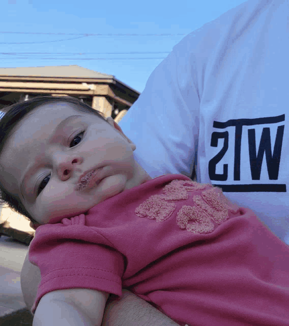 a baby is being held by a man wearing a shirt that says 2tw on it