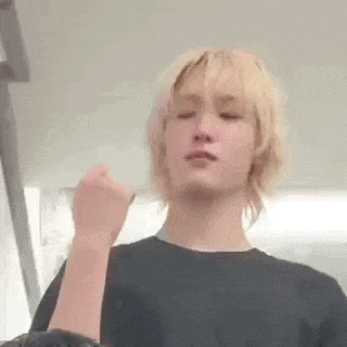 a man with blonde hair is making a funny face and giving a middle finger .