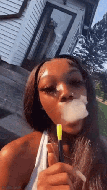 a young woman is smoking a cigarette in front of a house .