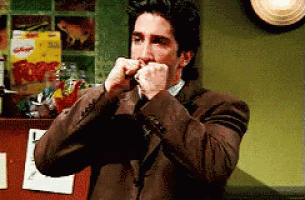 a man in a suit is covering his mouth with his hands in front of a box of kelloggs cereal .