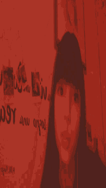 a girl is taking a selfie in front of a wall that says " enjoy "
