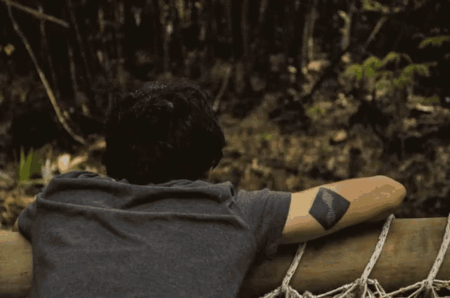 a man with a tattoo on his arm looks over a wooden railing