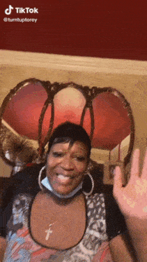 a woman wearing a mask and hoop earrings is waving her hand in front of a lamp ..
