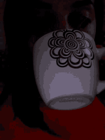 a white mug with a black and white flower on it