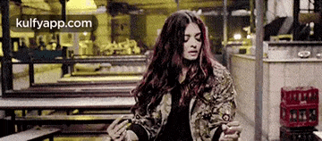 a woman with long hair is sitting at a table in a restaurant .
