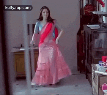 a woman in a pink dress is standing in a room .
