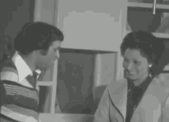a man and a woman are standing next to each other in a room and talking to each other .