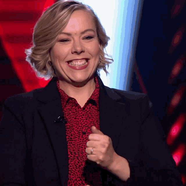 a woman wearing a black jacket and red shirt is smiling