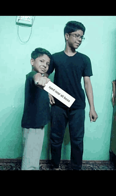 two young boys standing next to each other with one holding a card that says eyed isnar ali boss