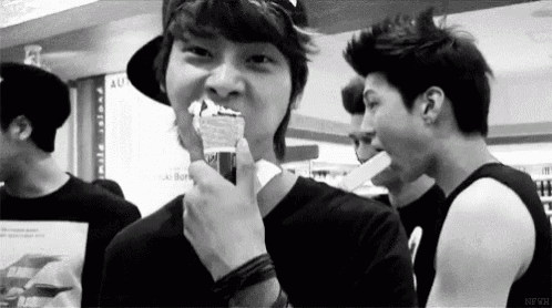 a group of young men are standing next to each other in a room and one of them is eating something .