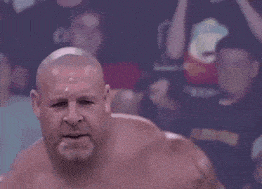 a bald man is laying down in a wrestling ring with his head down .