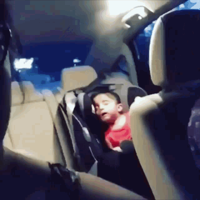 a baby is sleeping in a car seat in the back