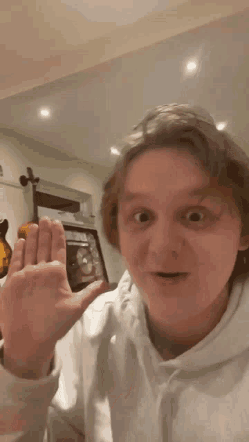 a man in a white hoodie is making a funny face with his hand