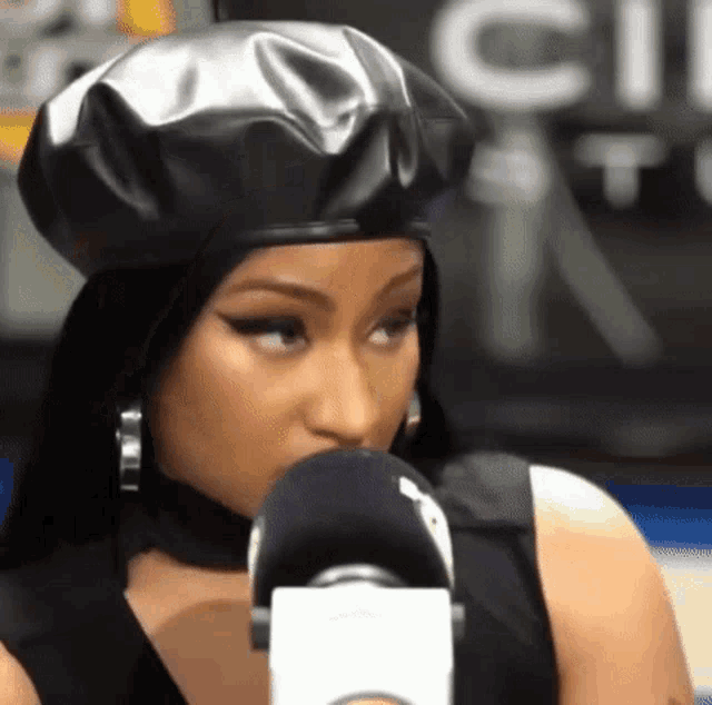 a woman wearing a black beret is talking into a microphone and making a funny face .