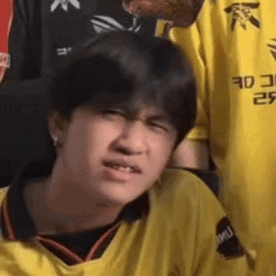 a young man in a yellow shirt is making a face .