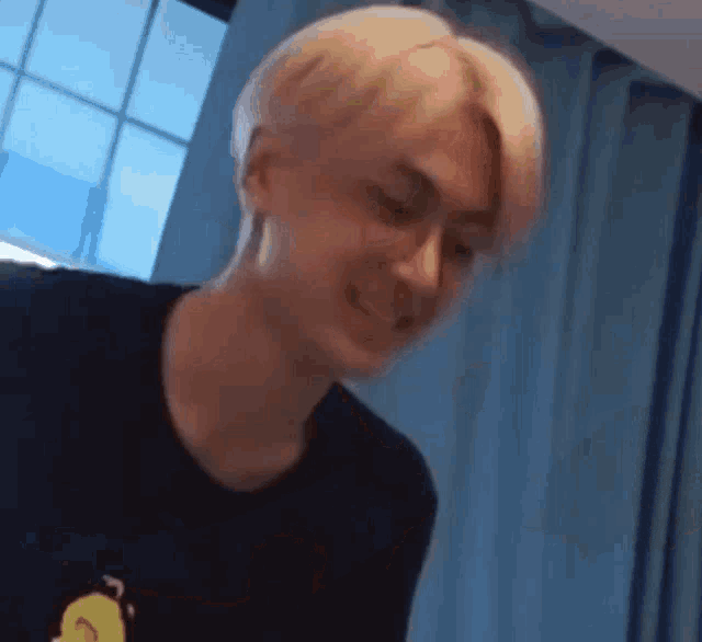 a young man with blonde hair is making a funny face while sitting in a room .