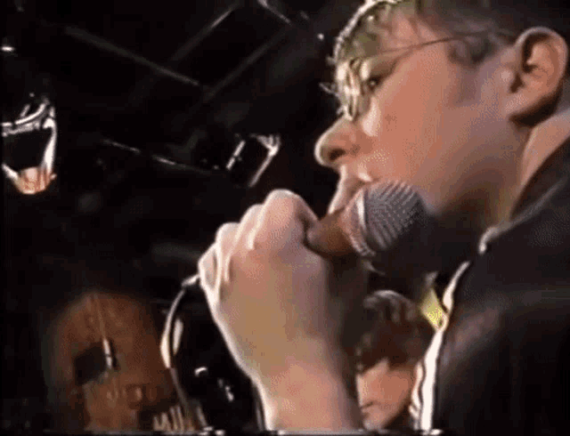 a man is singing into a microphone while wearing glasses