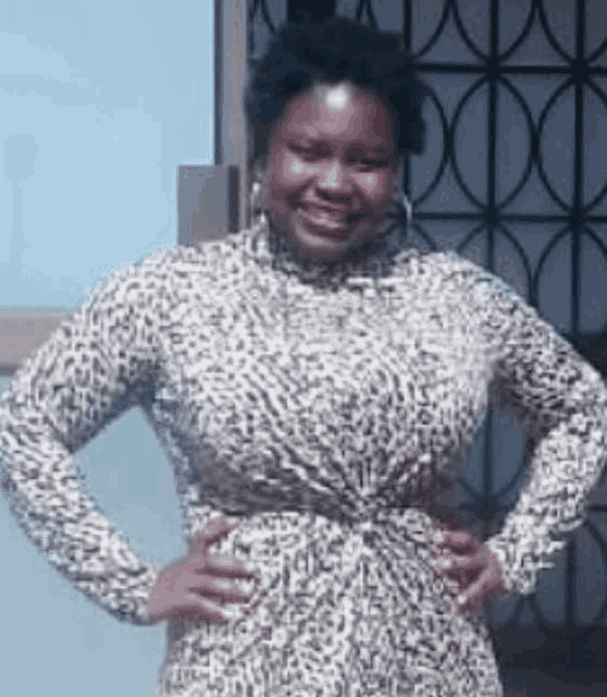a woman wearing a leopard print dress is standing with her hands on her hips .