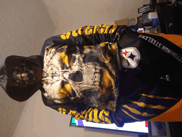 a man wearing a pittsburgh steelers hoodie with a skull on it