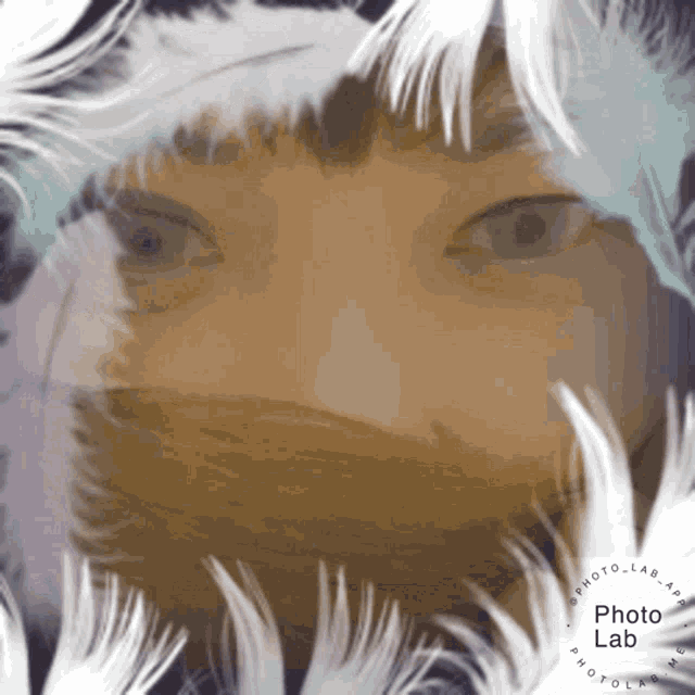 a close up of a person 's face surrounded by white feathers with a photo lab logo in the middle