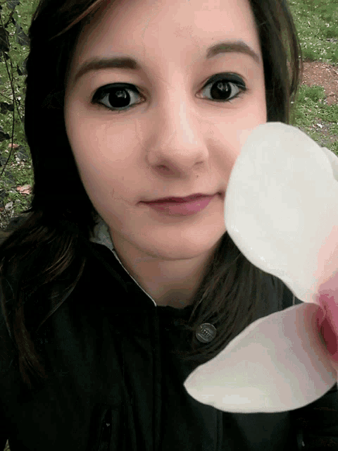 a woman holds a white flower in her hand