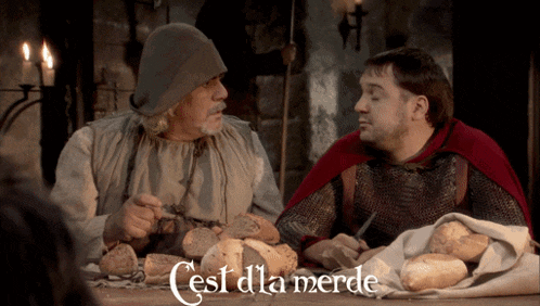 two men sitting at a table with bread and the words cest d' la merde