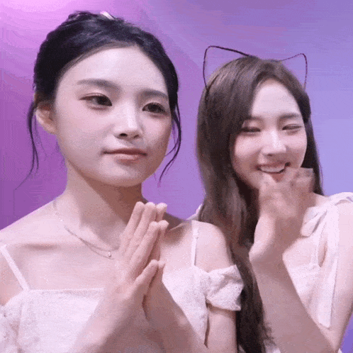 two girls are posing for a picture and one has cat ears on