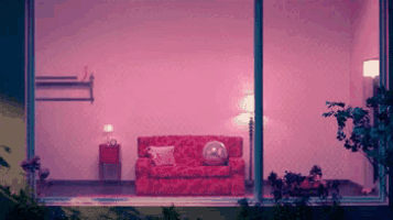 a living room with a red couch and pink walls is seen through a window .