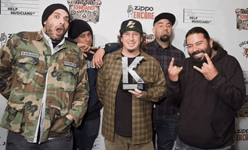 a group of men are posing for a picture in front of a zippo sign