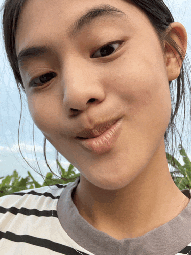 a close up of a person 's face with a striped shirt on
