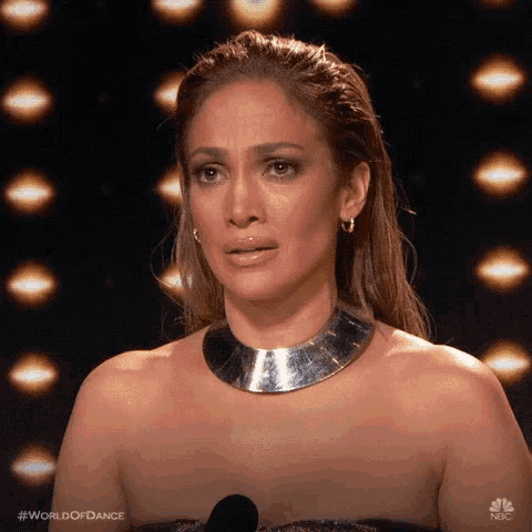 the woman is wearing a silver necklace and earrings and is crying .