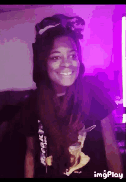 a woman is smiling in front of a purple background with the word imgplay on the bottom right