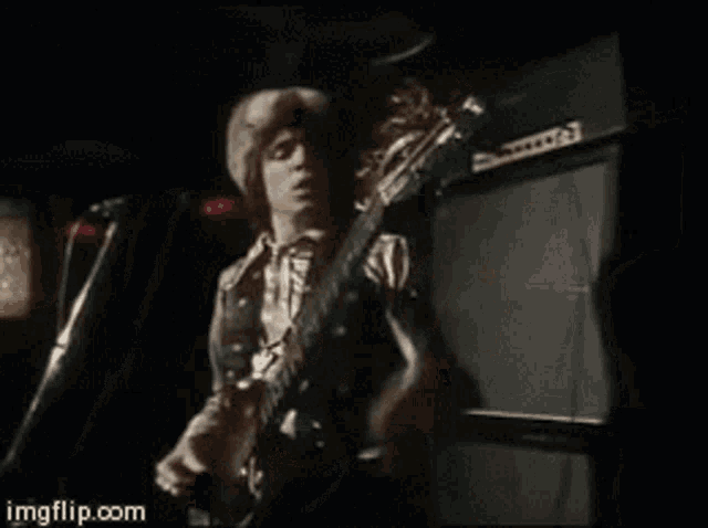 a man is playing a guitar in front of a microphone with the website imgflip.com in the corner