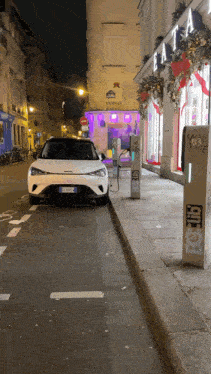 a white car is parked on the side of the road next to a sign that says betio