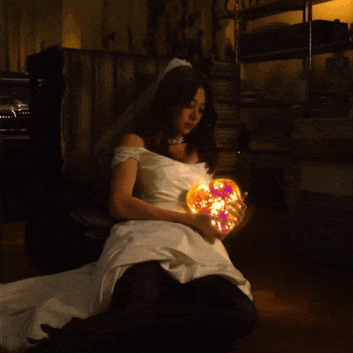 a woman in a wedding dress holds a glowing heart