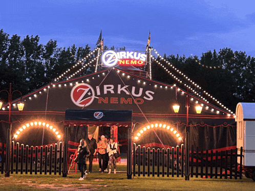 a group of people standing in front of a circus tent called zirkus nemo