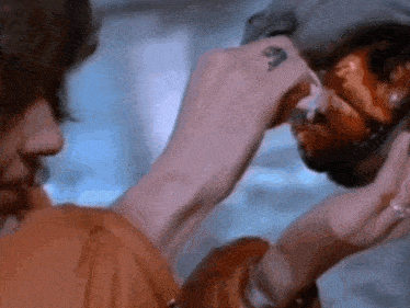 a woman is applying makeup to a man 's face with a syringe .