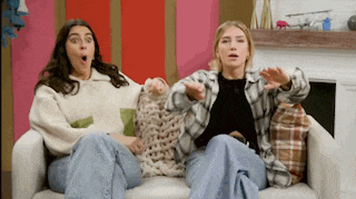 two women are sitting on a couch with their arms outstretched