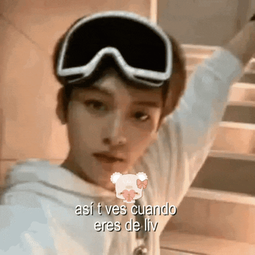 a young man wearing a pair of ski goggles is standing in front of a staircase .