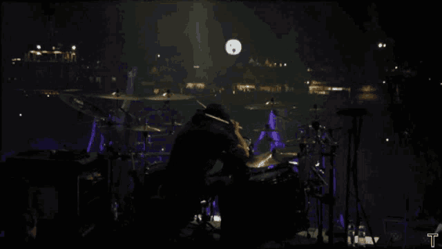 a man playing drums in a dark room with a t on the bottom