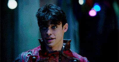 a man in a red leather jacket is standing in a dark room looking at the camera .