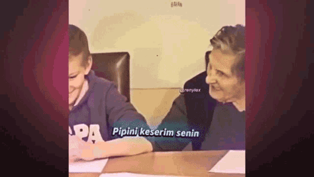 a man and a boy are sitting at a table . the boy is laughing and the man is laughing .