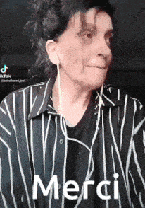 a woman wearing earphones and a striped shirt says merci .