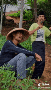 a man wearing a straw hat is sitting next to another man wearing a tik tok shirt