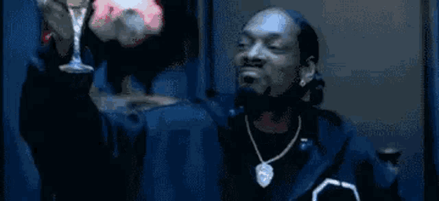 snoop dogg is wearing a fur coat and tie while holding a microphone .