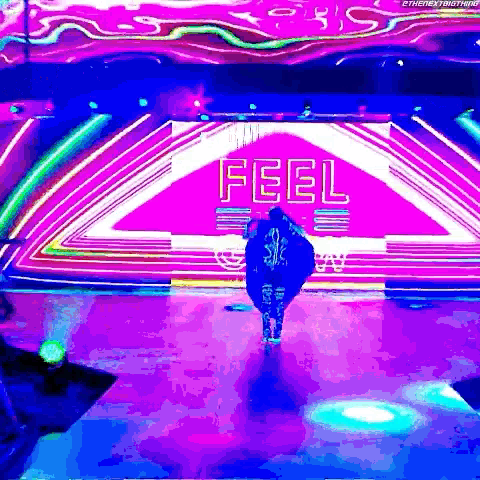 a person is walking on a stage with a sign that says feel