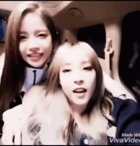 two girls are sitting in a car and smiling at the camera .